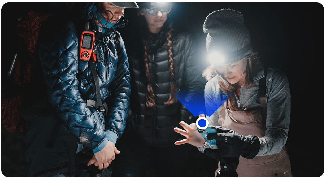 3 women backpacking at night looking at GPS on a phone 