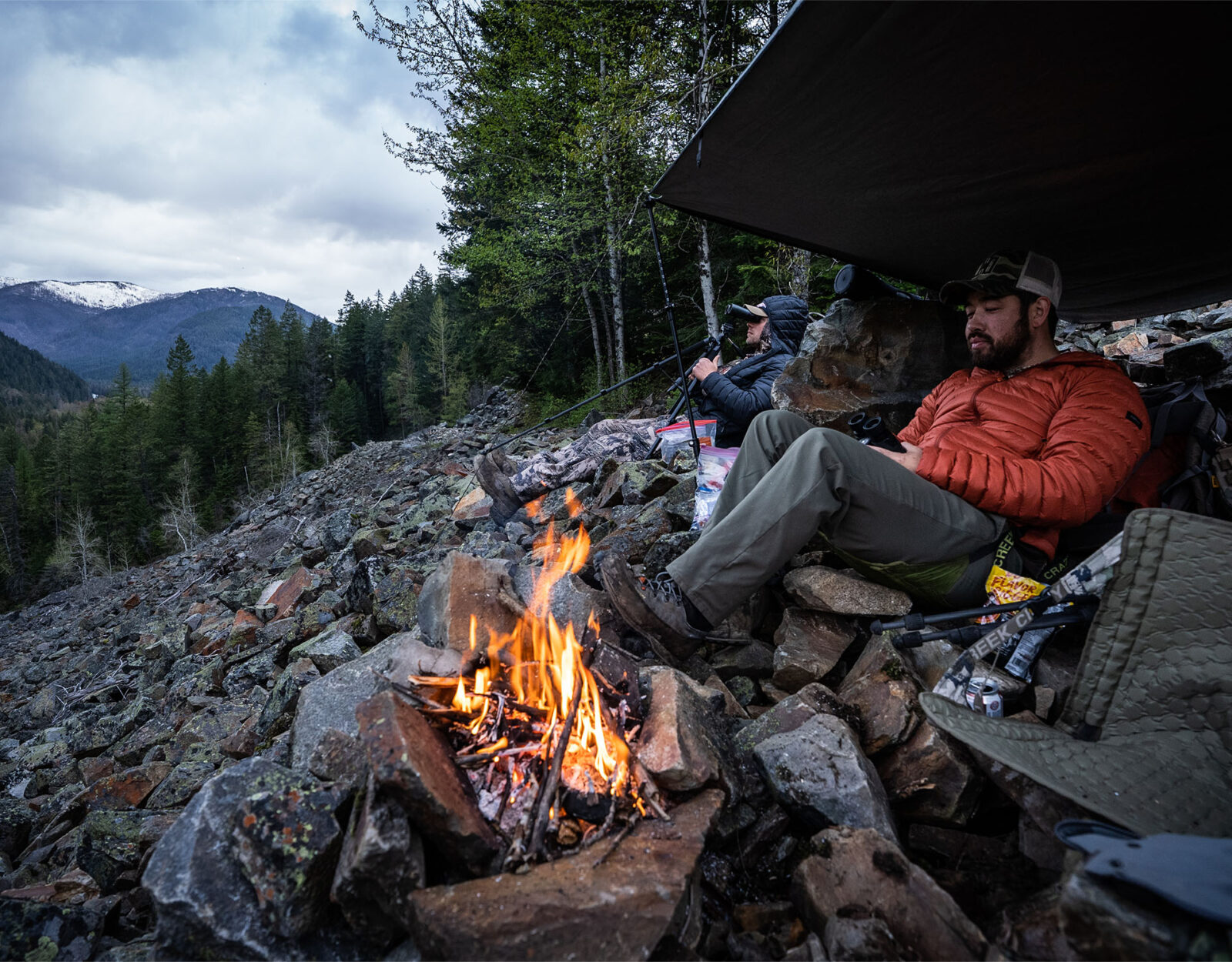 Essential hunting gear being used by 2 hunters around a camp fire