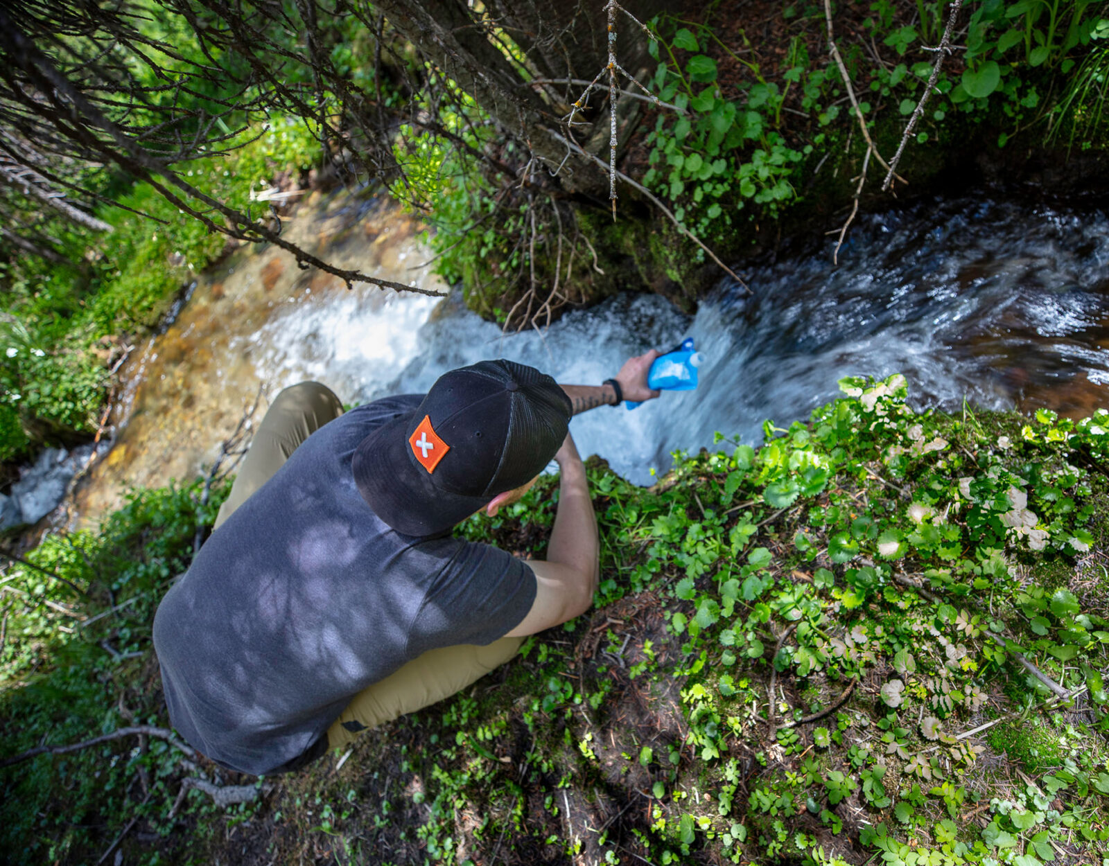 a hunter putting water into a water purification system from a river 