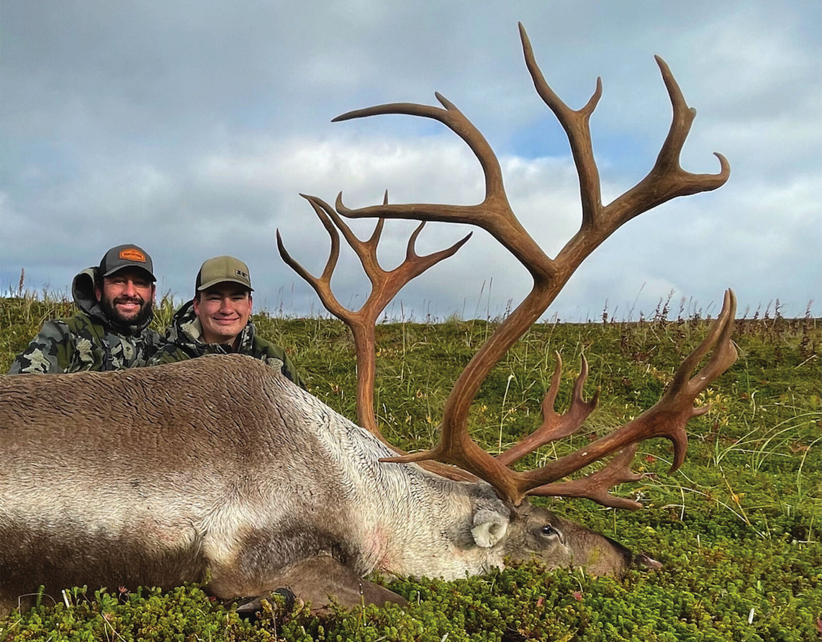 Two hunters pose with an elk