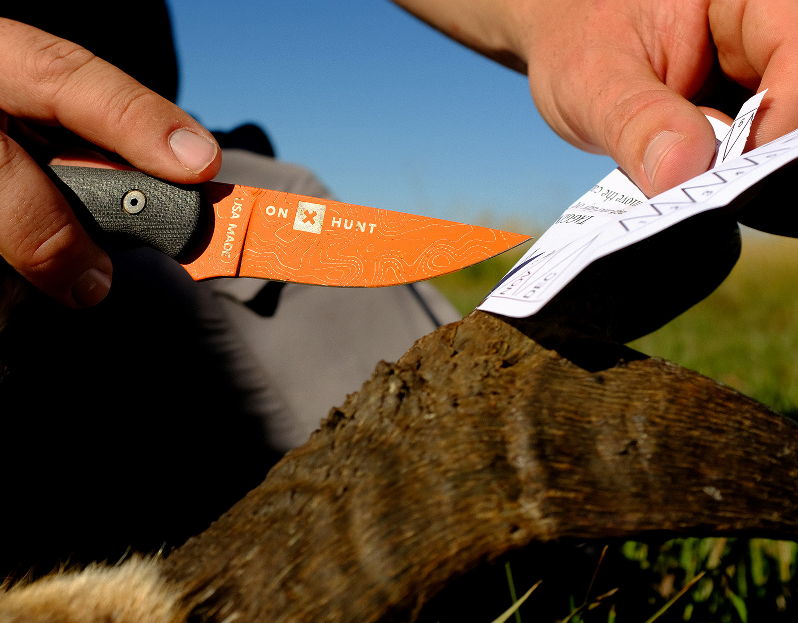 an onX Hunt knife cutting a hunting application tag 