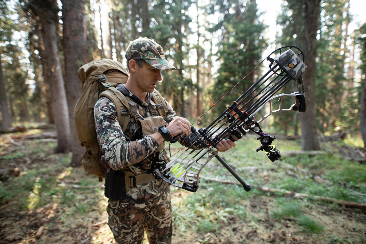 Hunter with a mobile camp - backpack on his back with his tent in the backpack, and his bow ready to go hunting.