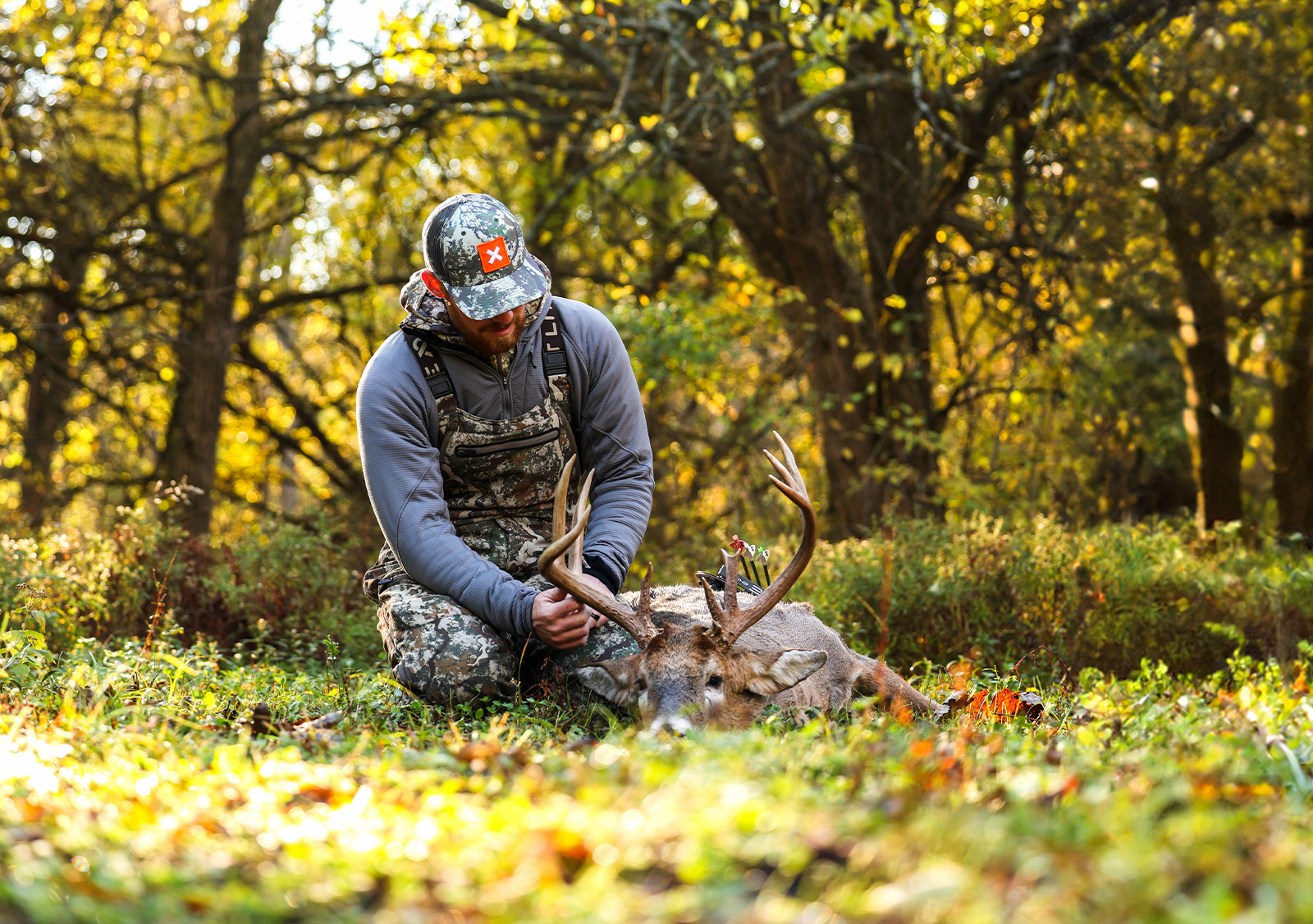 Hunter with a harvested deer in a field. 