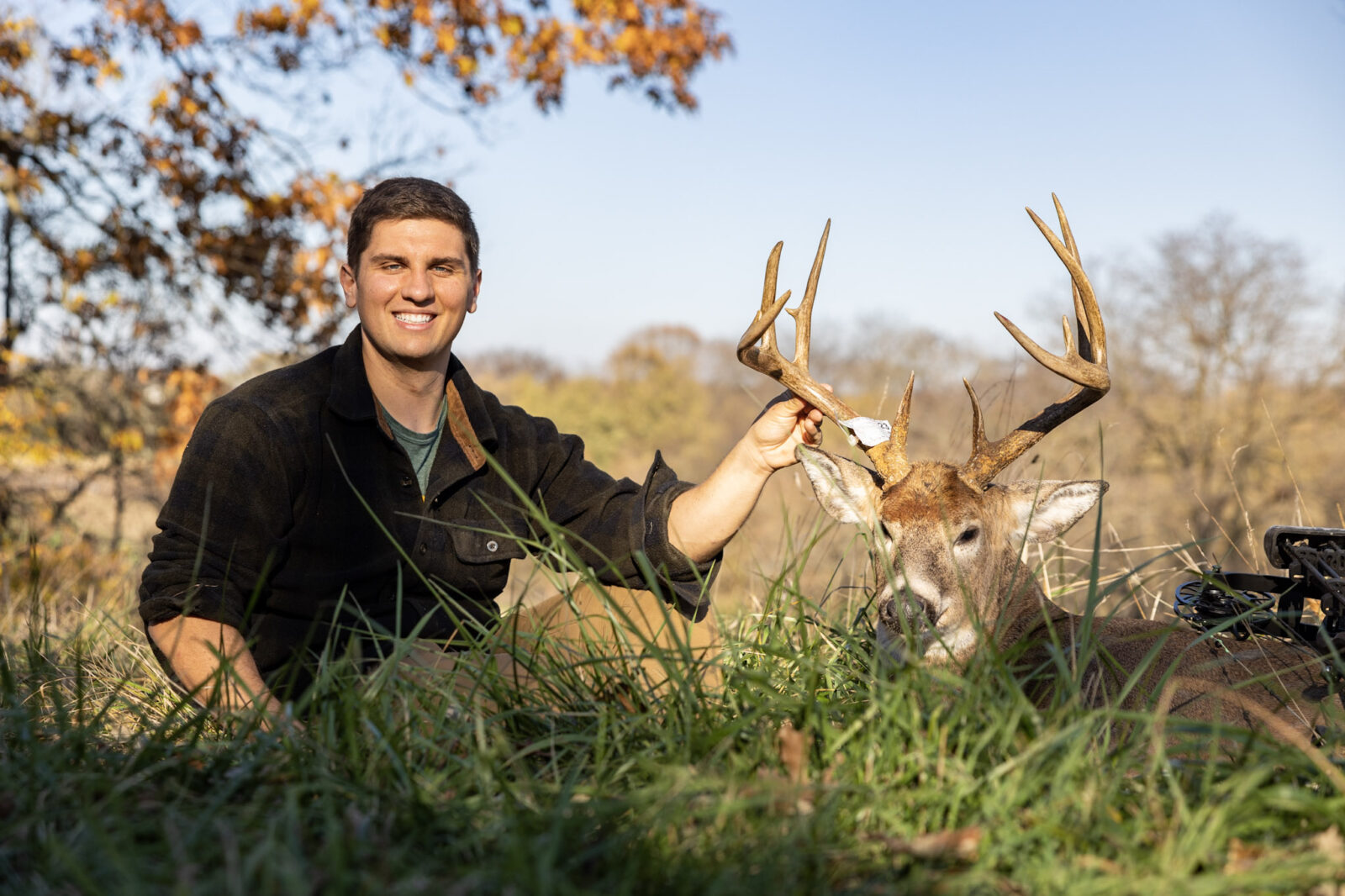 A hunter with a deer he successfully harvested in a grassy field.