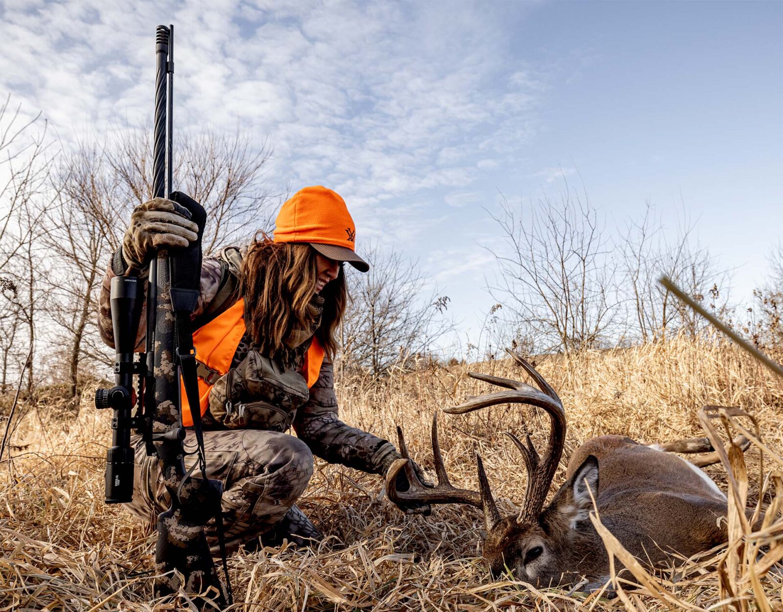 A hunter admires the deer she harvested with her muzzleloader.