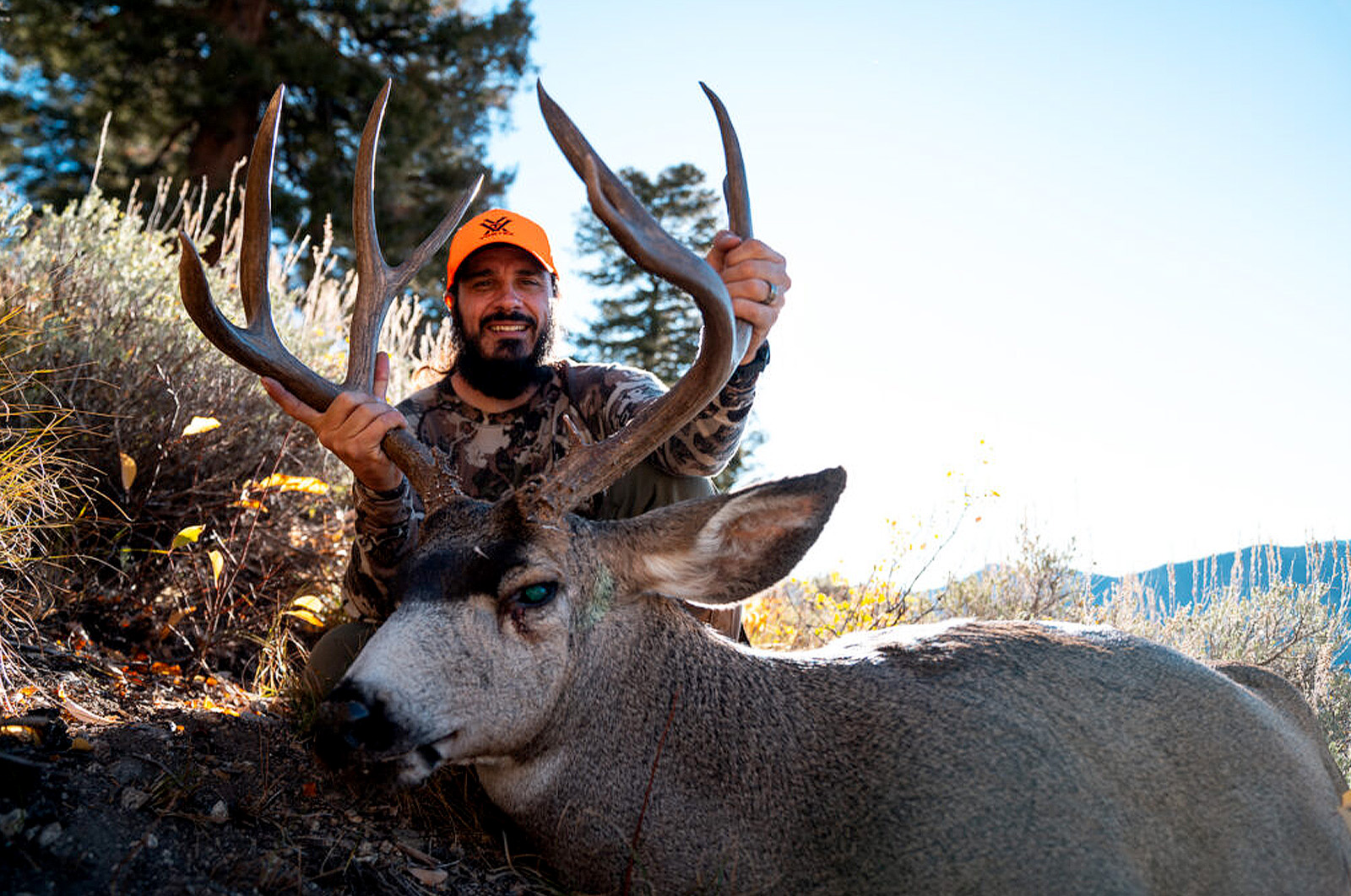 Man with mule deer that he shot while hunting in the mountains. 