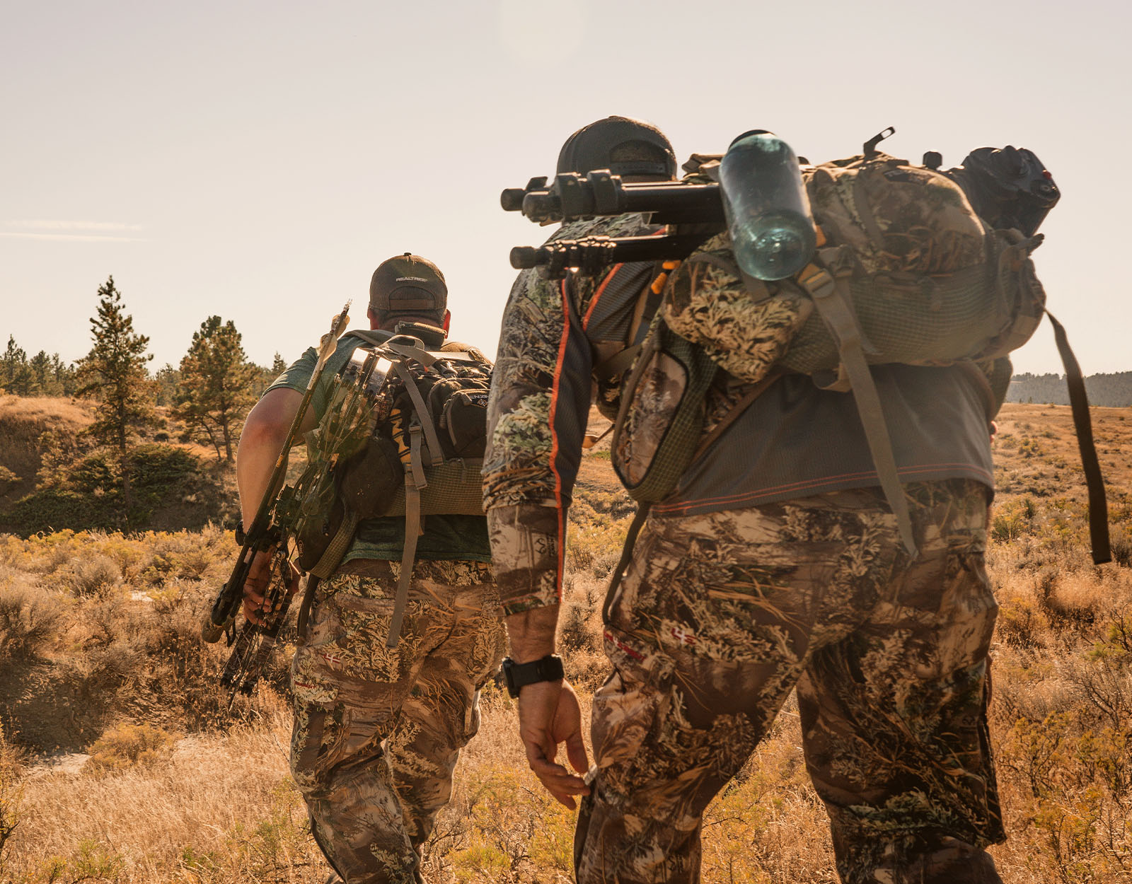 Two hunters stalk through prairie land. 