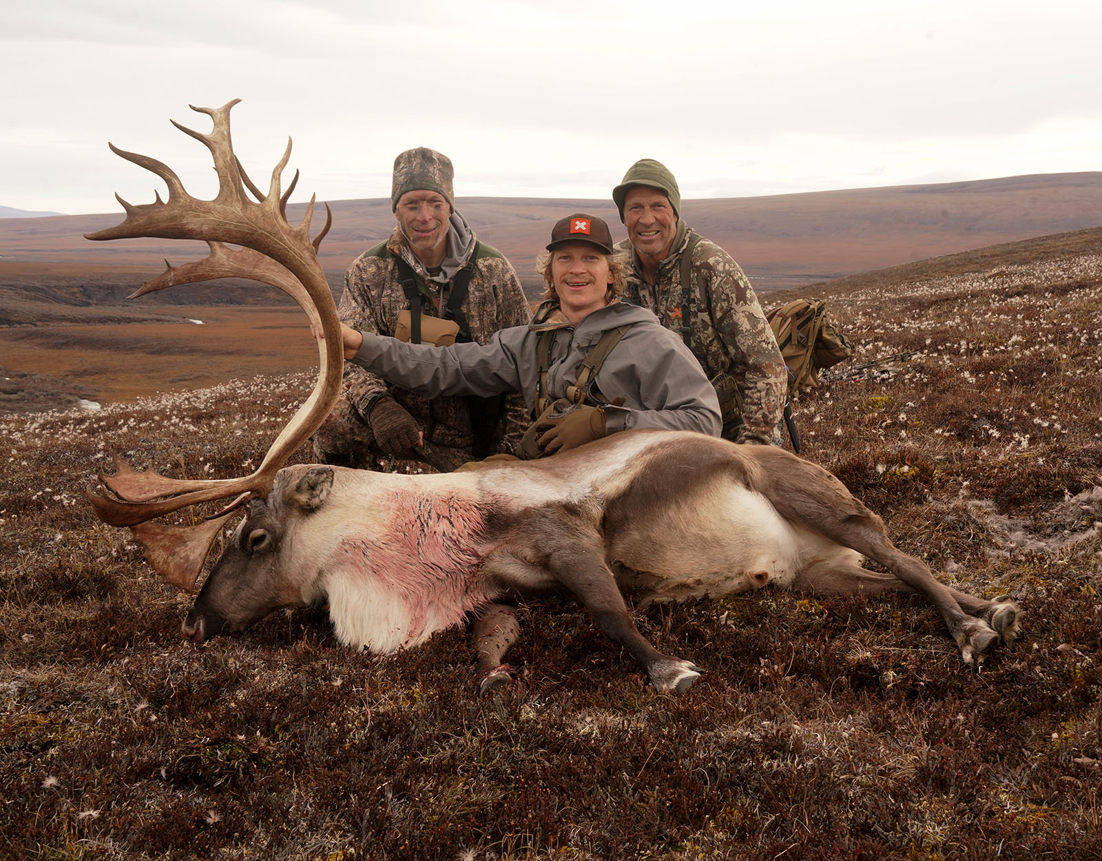 Three hunters pose with the bull caribou one of them harvested.