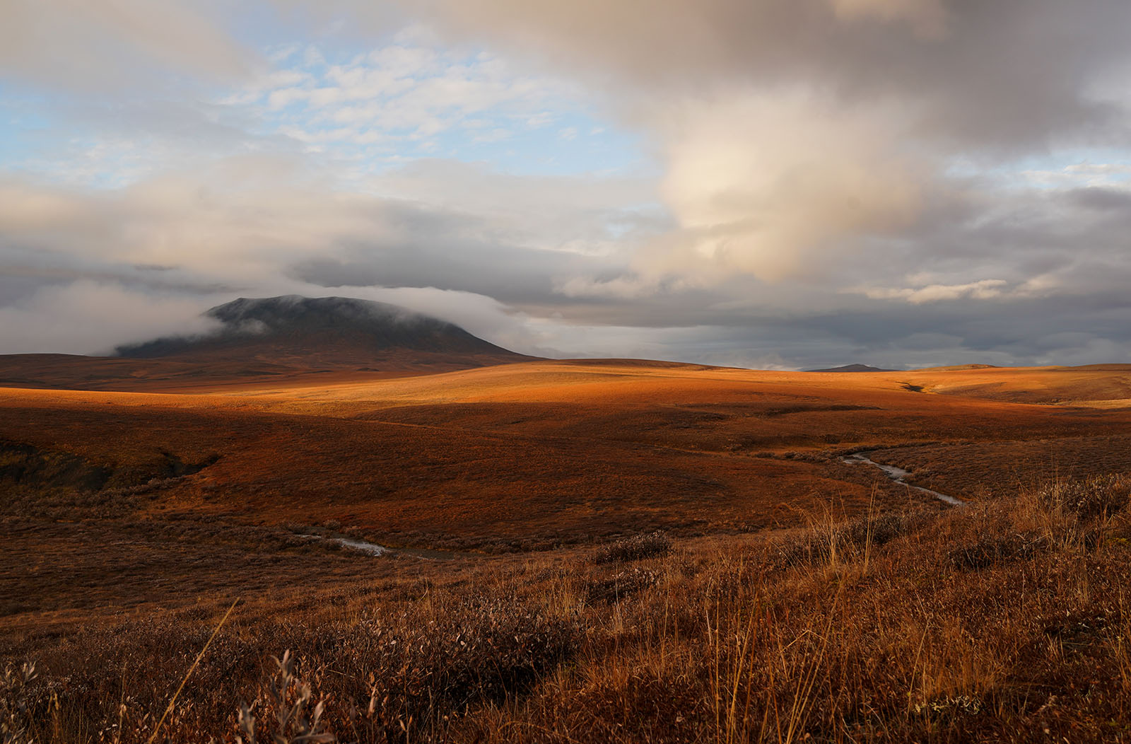 A remote and rugged landscape with low clouds. 