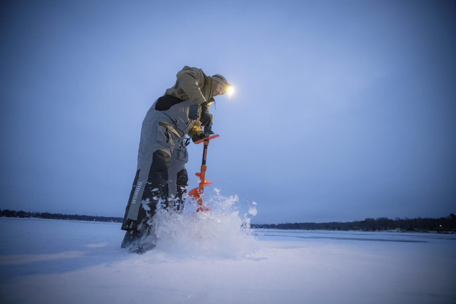 Man drilling ice fishing hole