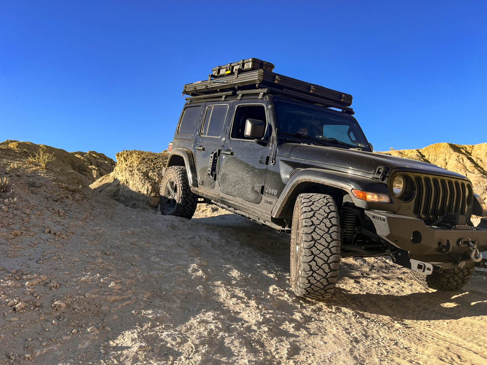 Black jeep off-roading down a dirt trail 