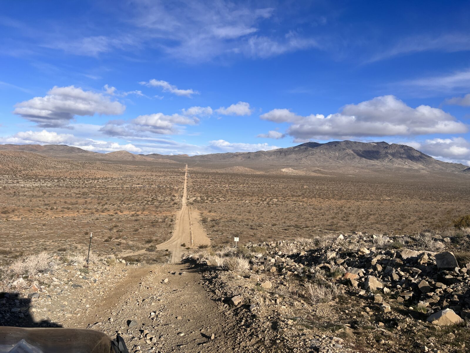 A dirt off-road trail leading to foot hills in a deserted landscape