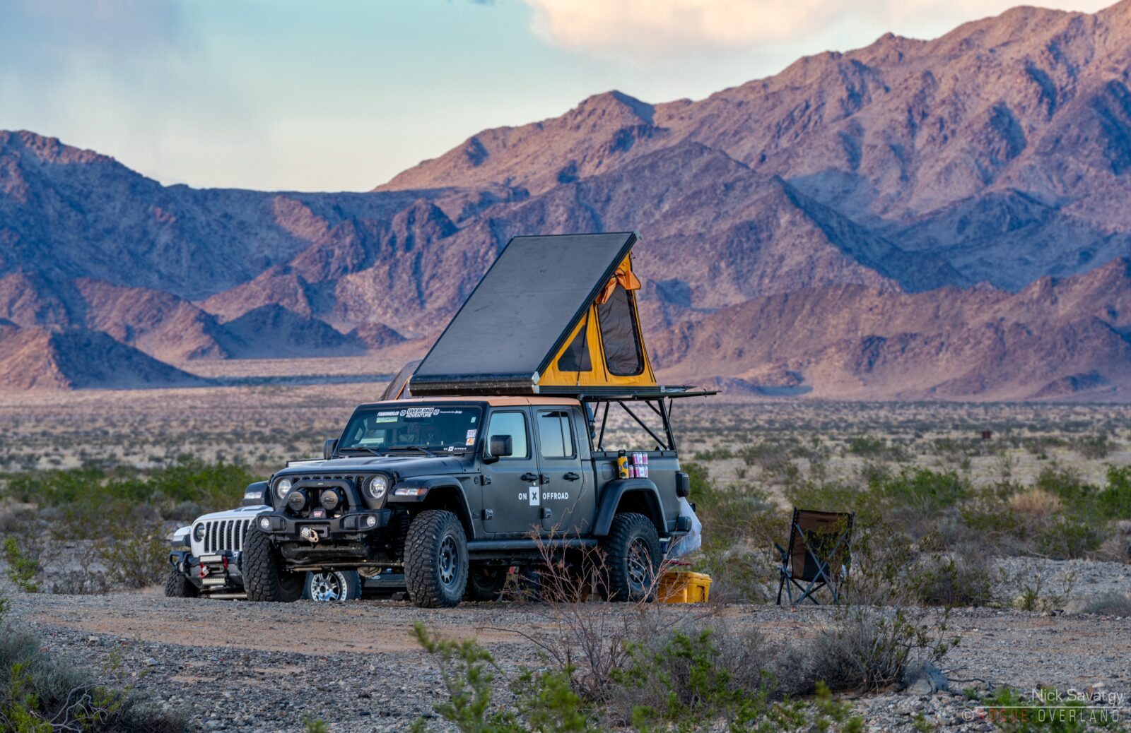 off-roading vehicle with a camper on top in a mountainy area